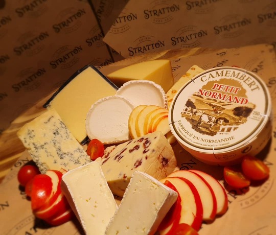 Delicious Cheeses available from Stratton Food Hall Platter of different cheeses decorated with fruit
